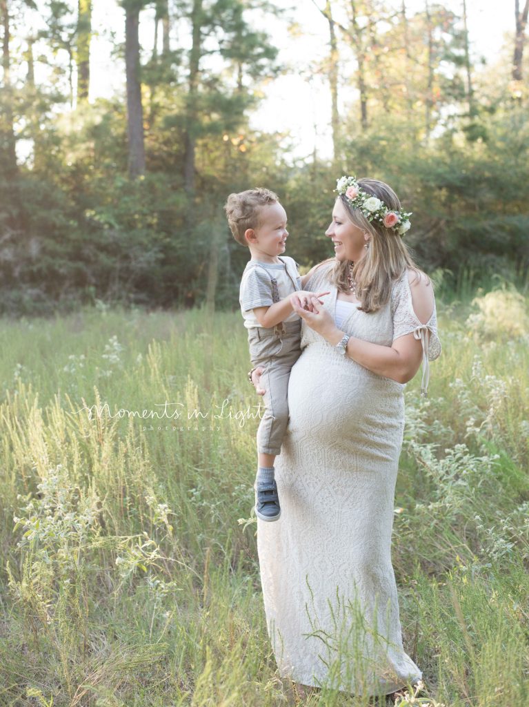 maternity photo of pregnant woman holding son in a field in The Woodlands, TX at sunset