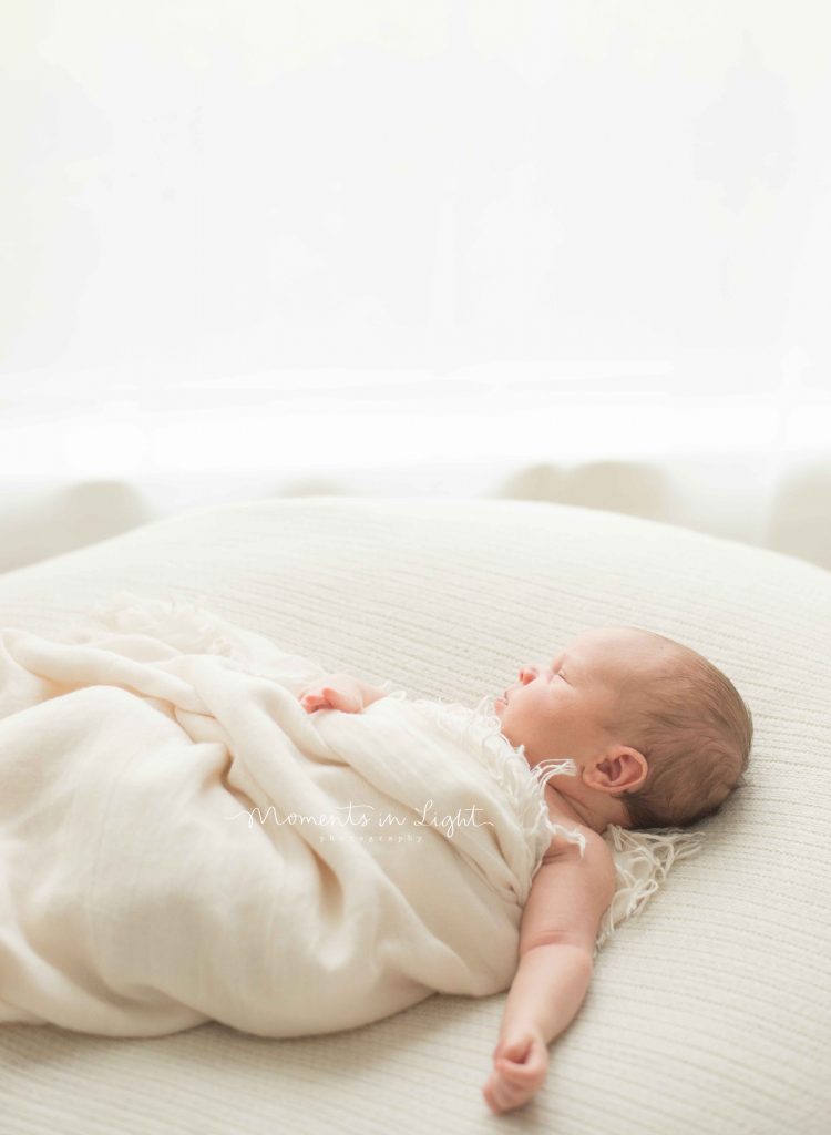 newborn baby on cream blanket wrapped by window in The Woodlands, TX