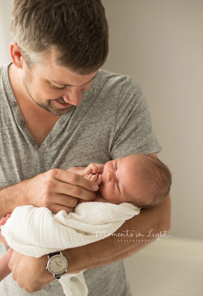 newborn baby smiling while dad holds him