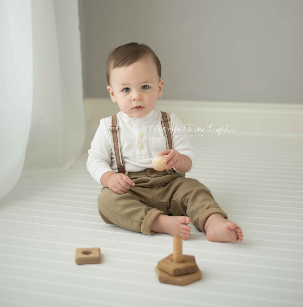 little boy in suspenders playing with wooden toys in photo studio in Montgomery, TX