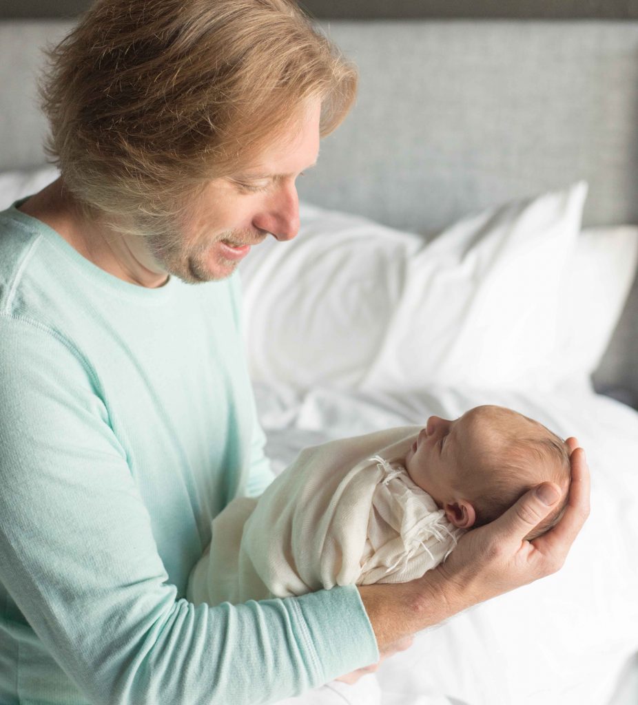 dad holding newborn baby girl and smiling down at her