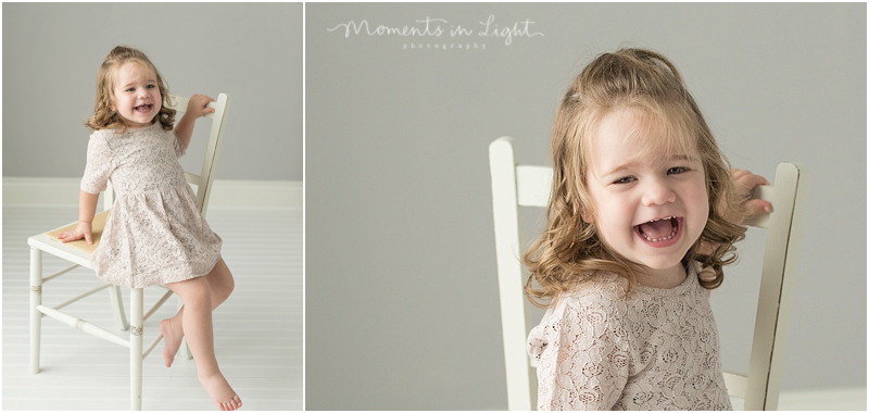 A professional child photographer captures a girl crawling off of a white chair. 