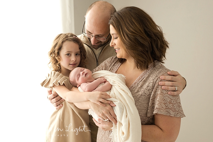 Mother, father and young girl holding swaddled baby boy by newborn photographer in Montgomery, Texas