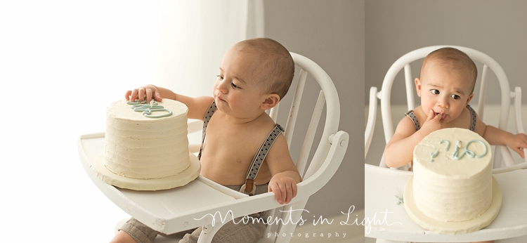 Boy eating frosting off first birthday cake in baby photography studio in Montgomery, Texas