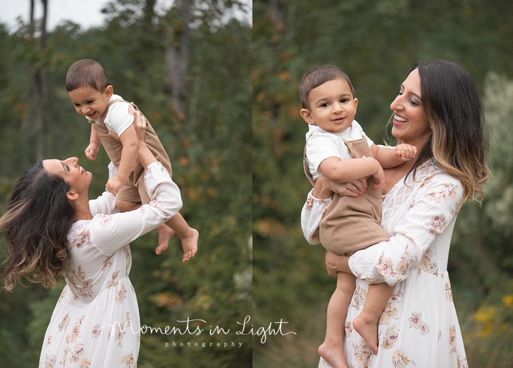 Woman in white floral dress smiling and holding up baby boy by Houston family photographer