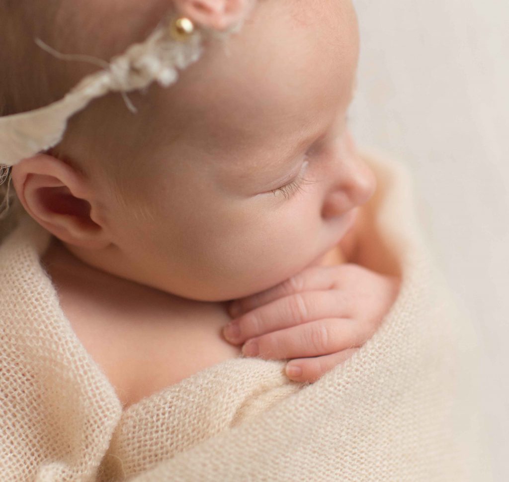 close up of newborn baby eyelashes and hands from above