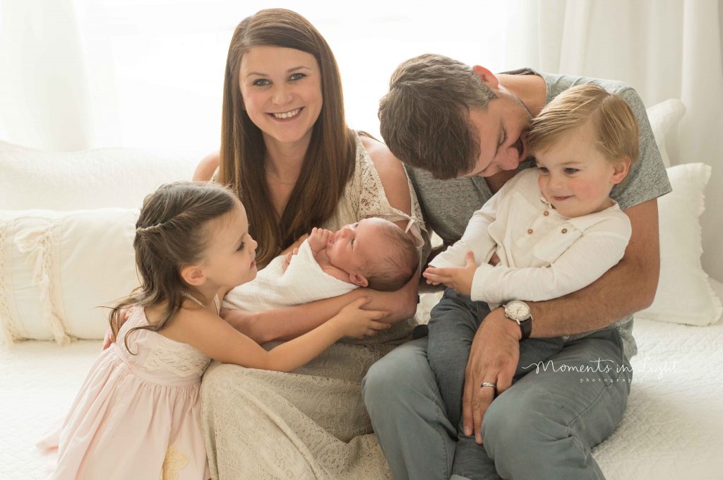 family with children and newborn baby smiling and laughing