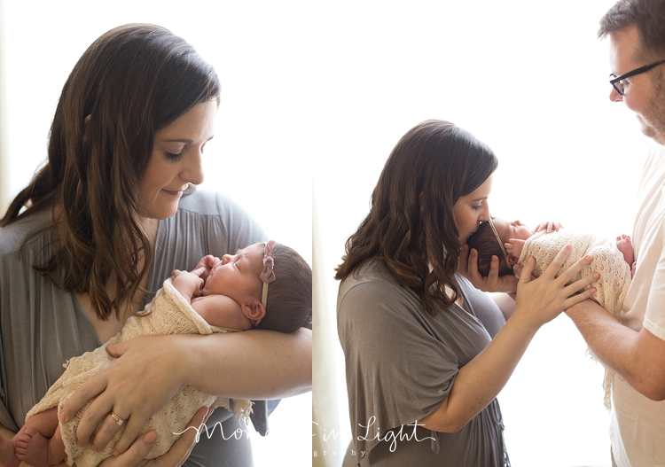 Baby held by mother and father in window of newborn photography studio in The Woodlands