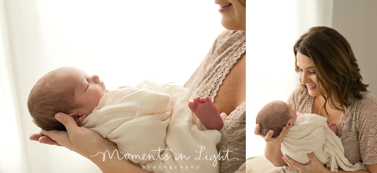 Mother in lace dress smiling down at newborn in photography studio in Montgomery, Texas