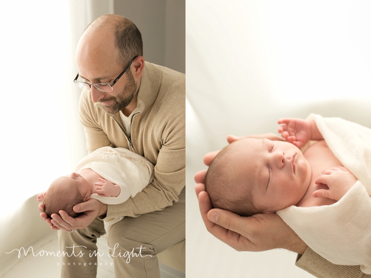 Father holding newborn baby boy's head in his hands in a photography studio in Houston