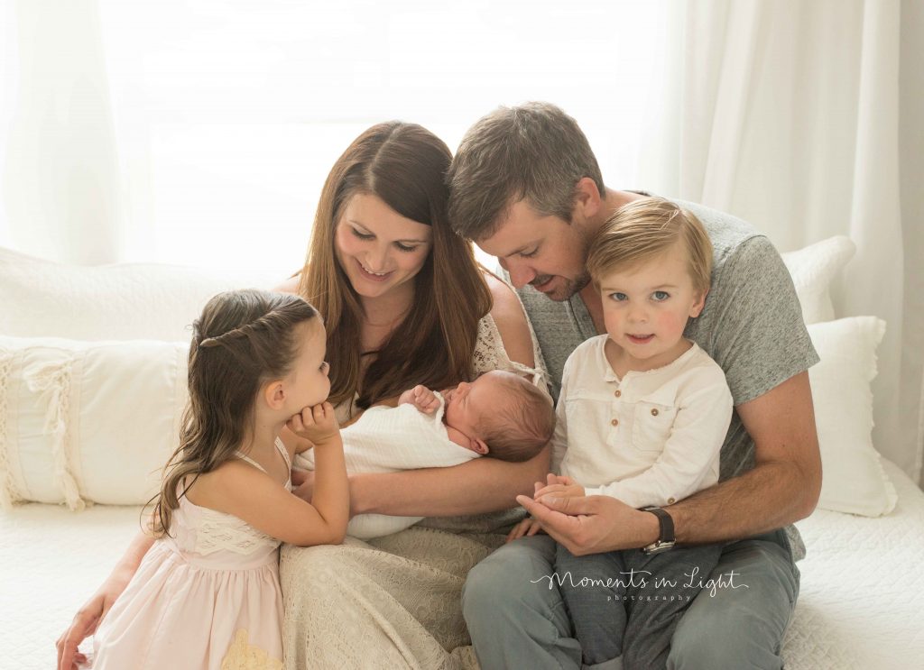 family looking and smiling at newborn baby