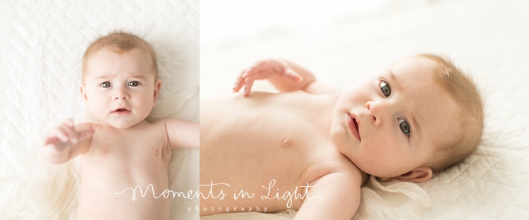 A baby is laying on a white blanket. 