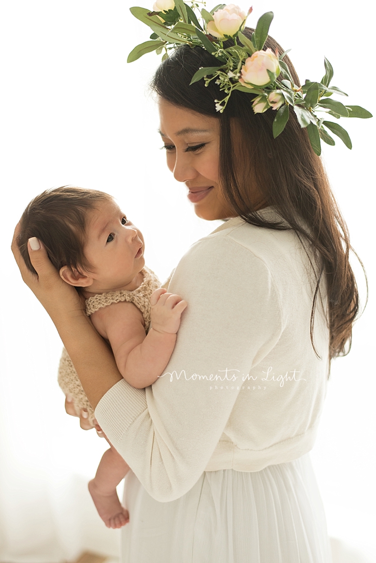 Baby looks over his mom's shoulders as she holds him in a Houston photo studio. 