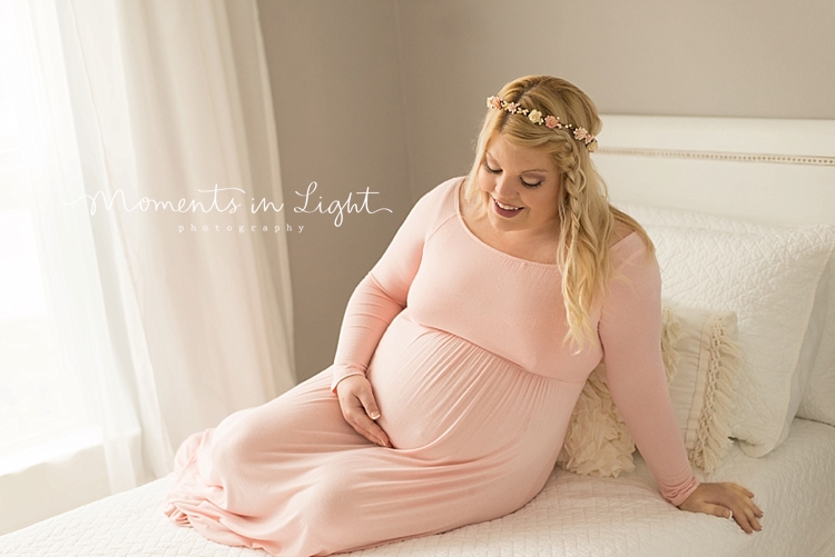 A pregnant woman wears a pink dress. 