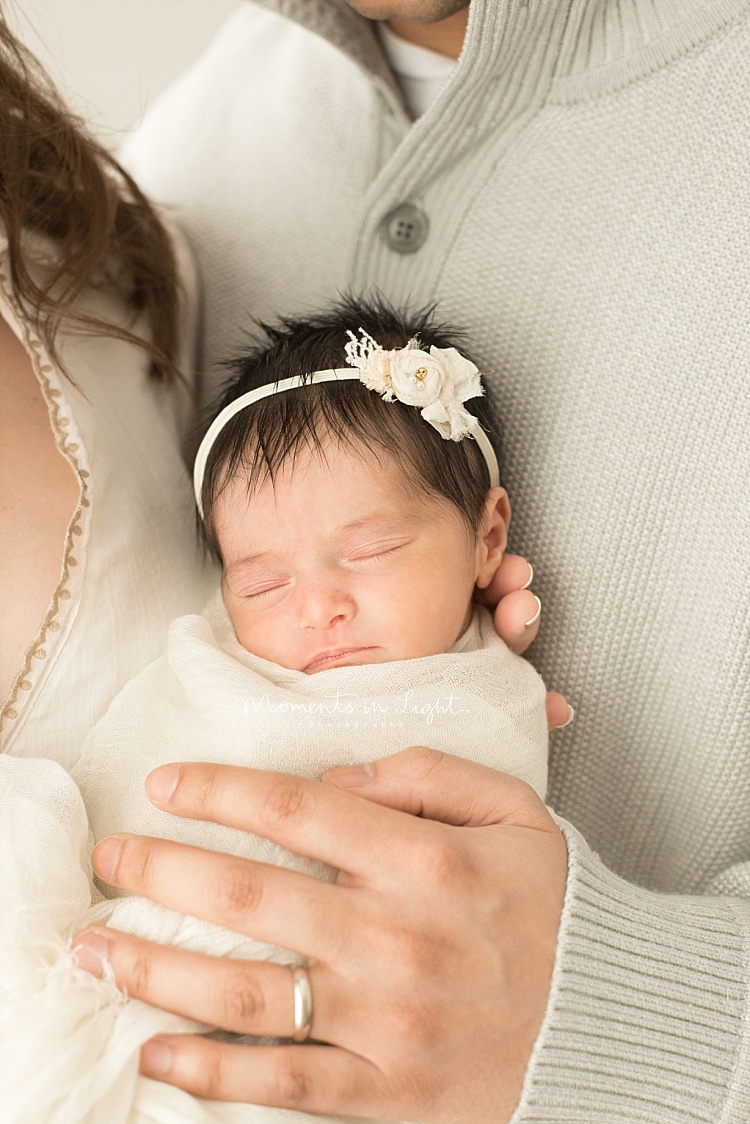 A baby sleeps in her parents' arms. 