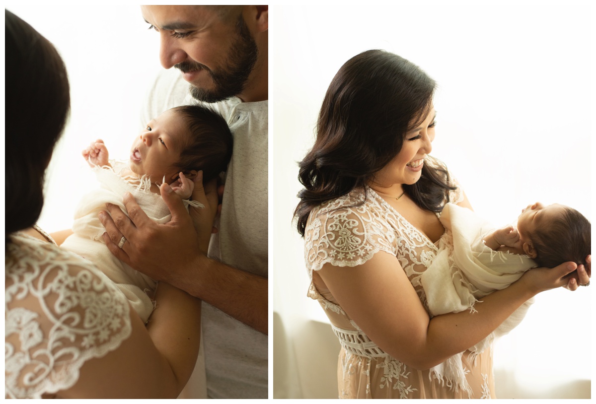 Mother and father holding their swaddled baby by a newborn photographer in The Woodlands