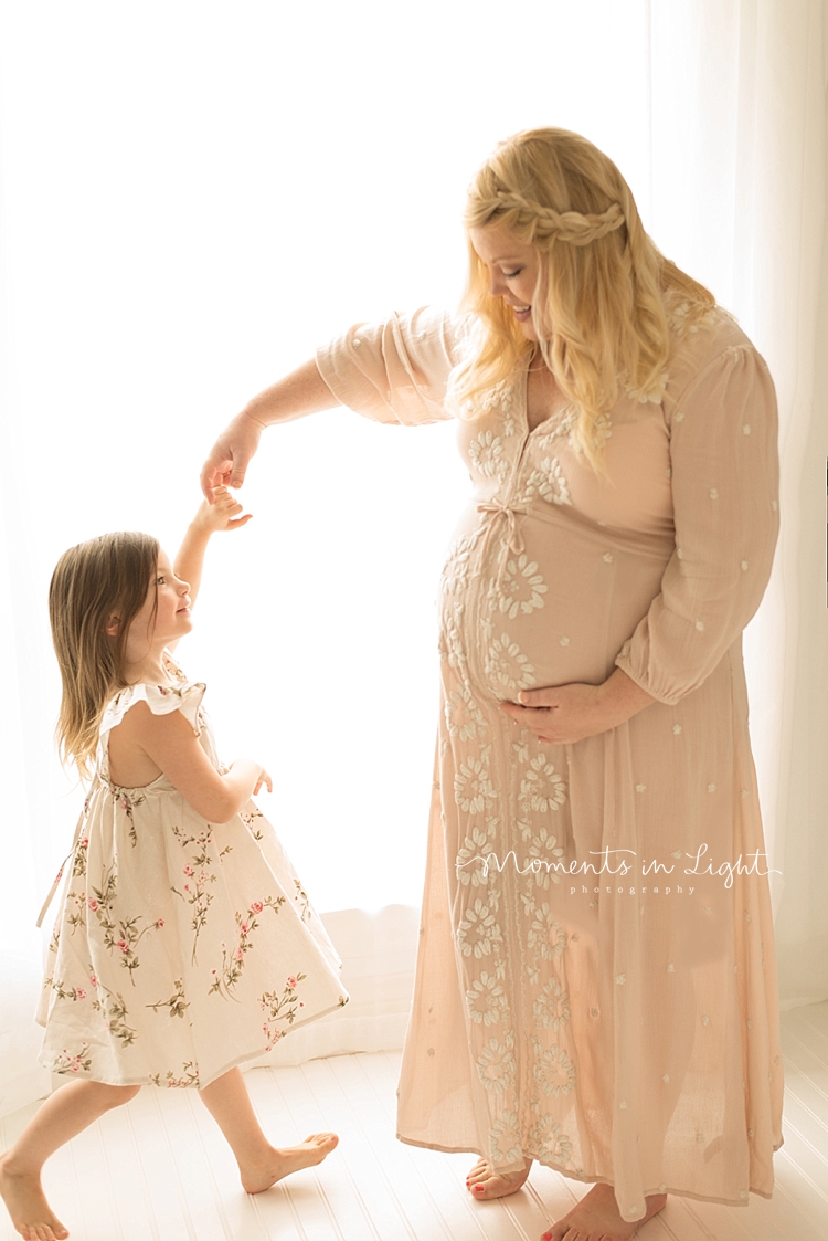 A pregnant mother dances with her daughter. 