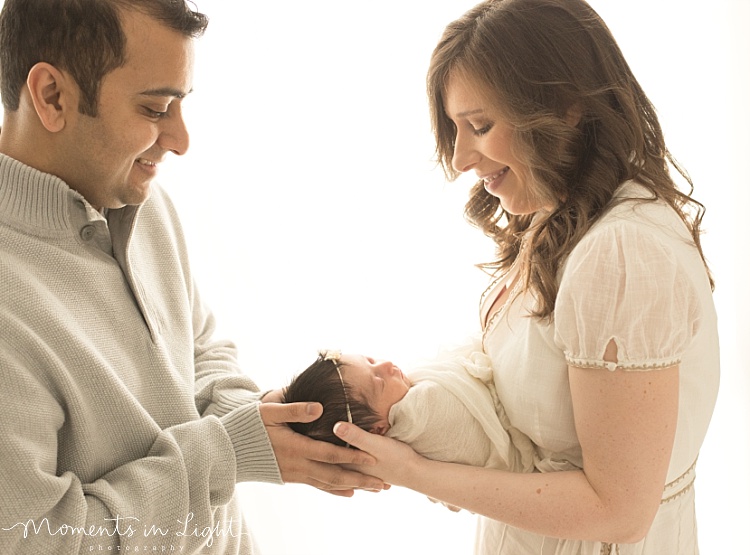 A new mom hands her baby to her husband. 