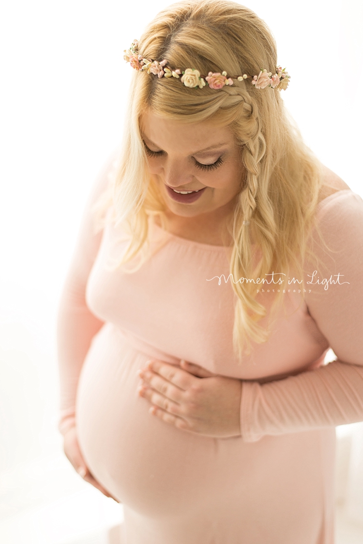 A woman smiles at her pregnant belly. 