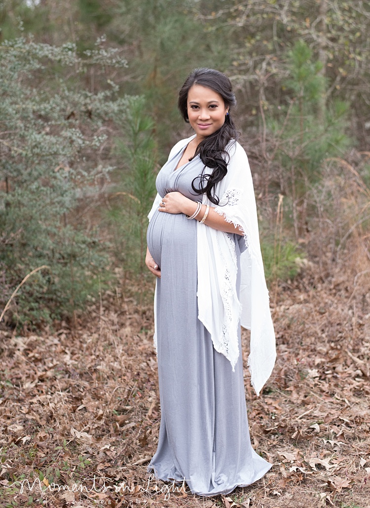 A pregnant woman holds her belly, posing for her outdoor maternity photos.