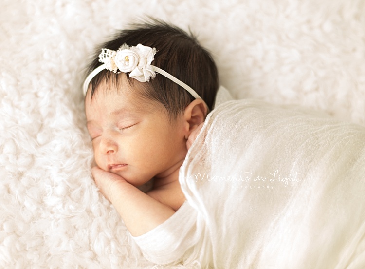 A baby sleeps with her hand under her head. 