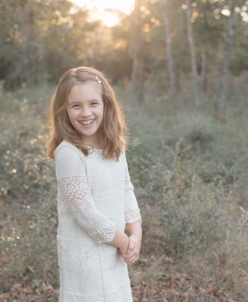 little girl smiling in a field with sunlight in Montgomery, TX