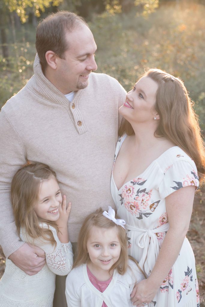 family with mom and dad smiling at each other in The Woodlands, TX