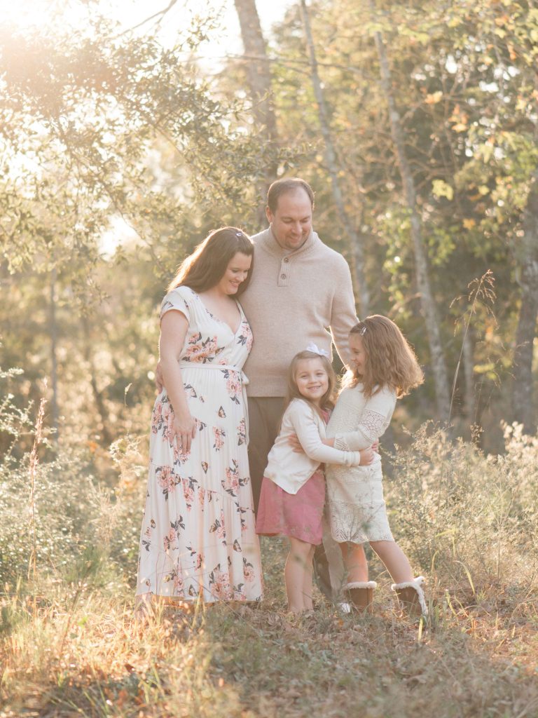 family of four with two little girls at sunset in field in The Woodlands, TX