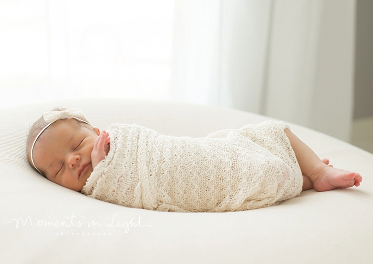 During a family with newborn photography session, a baby sleeps on a white bean bag. 