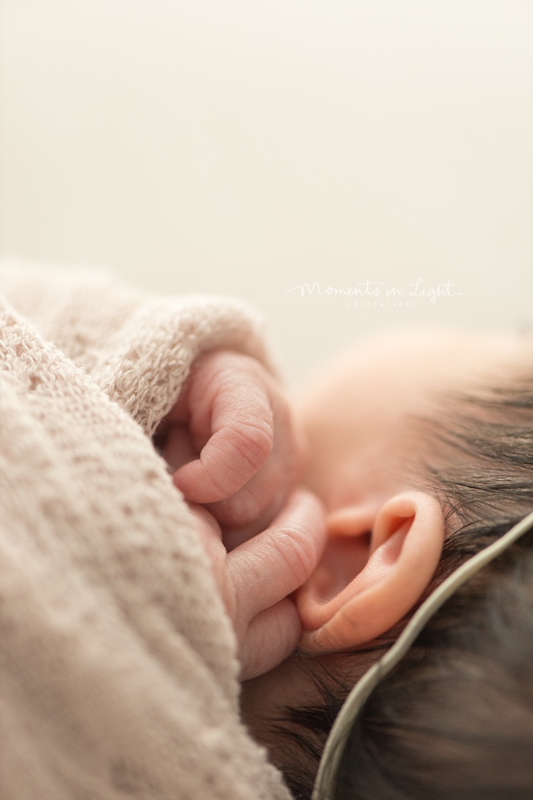 A baby holds her hands by her ear. 