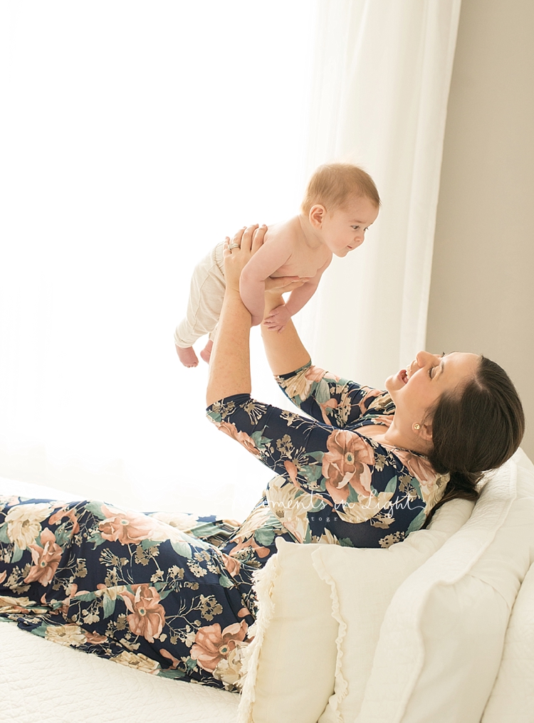 A mother holds her baby up in the air to play with him. 