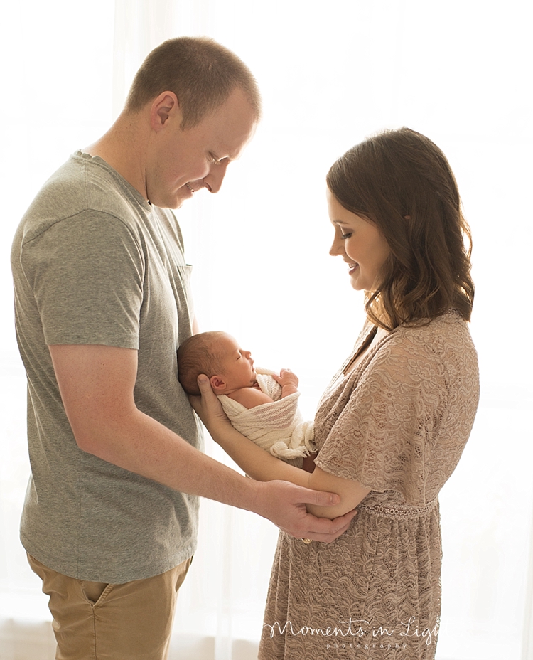 A new mom hands her baby to her husband. 