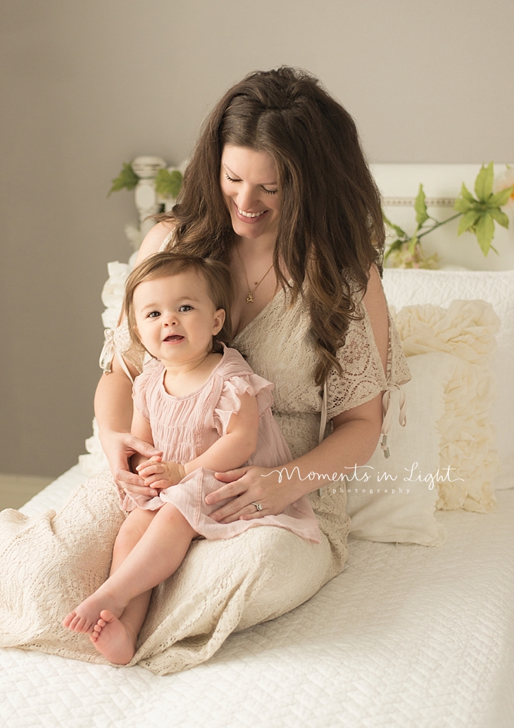 A mother holds her baby girl in her lap. 