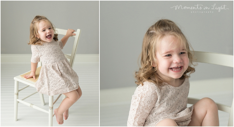 A girl scoots off of a white chair as she gives a hearty laugh. 