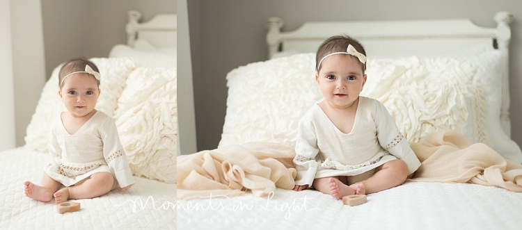 baby girl in linen dress on white bed in Houston photo studio 