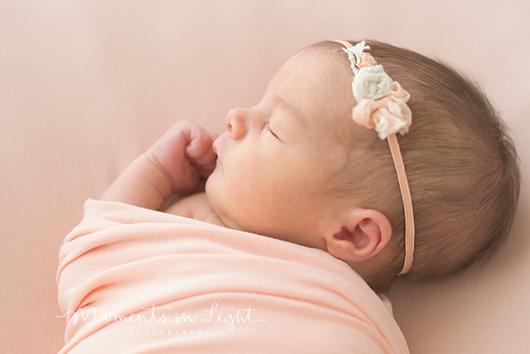 A newborn sleeps with her hand up during her family with newborn photography session. 