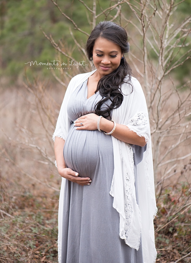 A pregnant mother wears a grey dress for her outdoor maternity photos. 