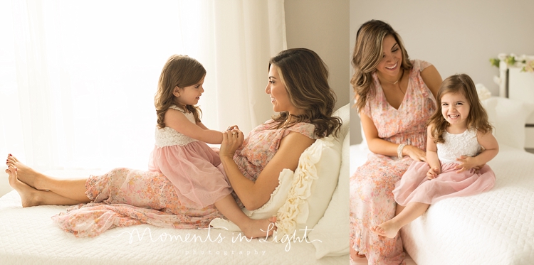 A girl sits on her mother's lap on a white bed to chat with her. 