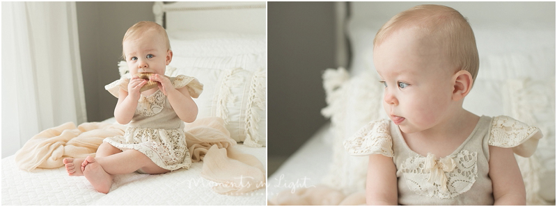 A baby girl with blue eyes puts a wooden toy in her mouth. 