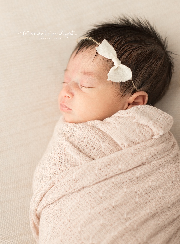 A newborn girl wears a bow. 