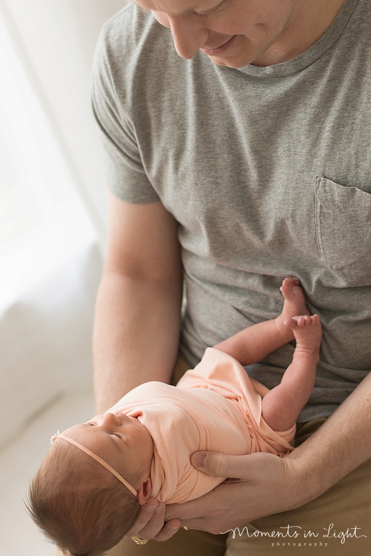 A baby sleeps on her daddy's lap as he holds her head gently. 