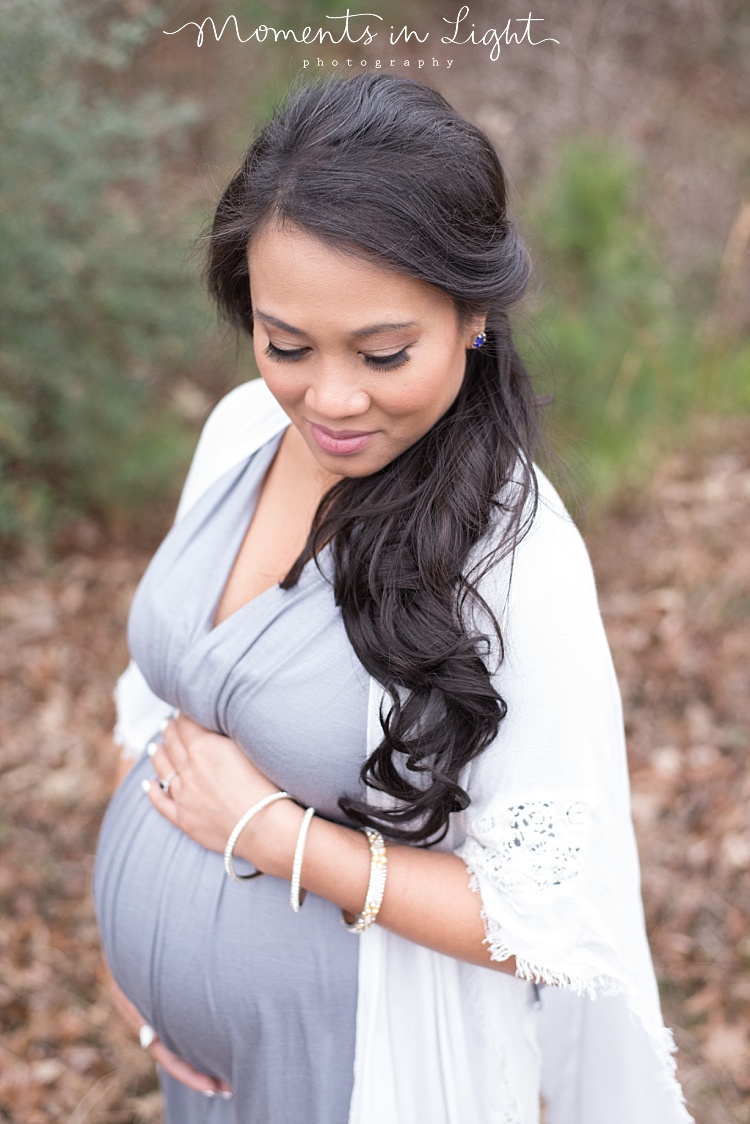 A pregnant mom looks down and holds her belly. 