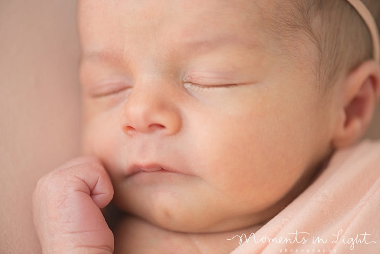 A baby's fist rests near her face as she sleeps peacefully. 