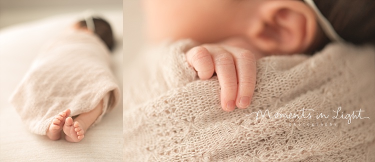 A baby's fingers peek out from her blanket. 