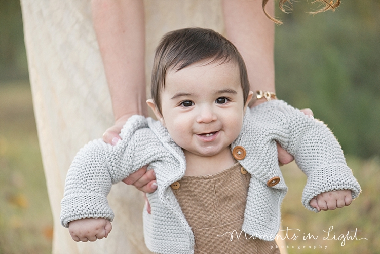 Baby boy in a grey sweater in a field by Montgomery, Texas family photographer