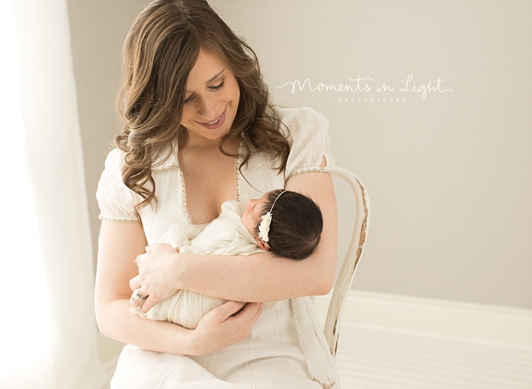 A new mother sits in a chair and holds her newborn. 