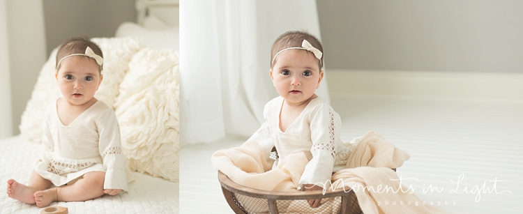 6-month-old baby girl in linen dress sitting on white bed 