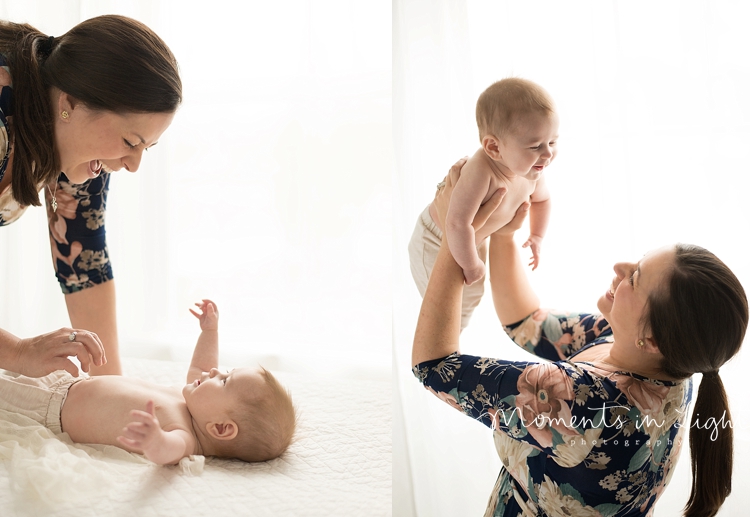 A mother bends over her baby boy to play with him. 