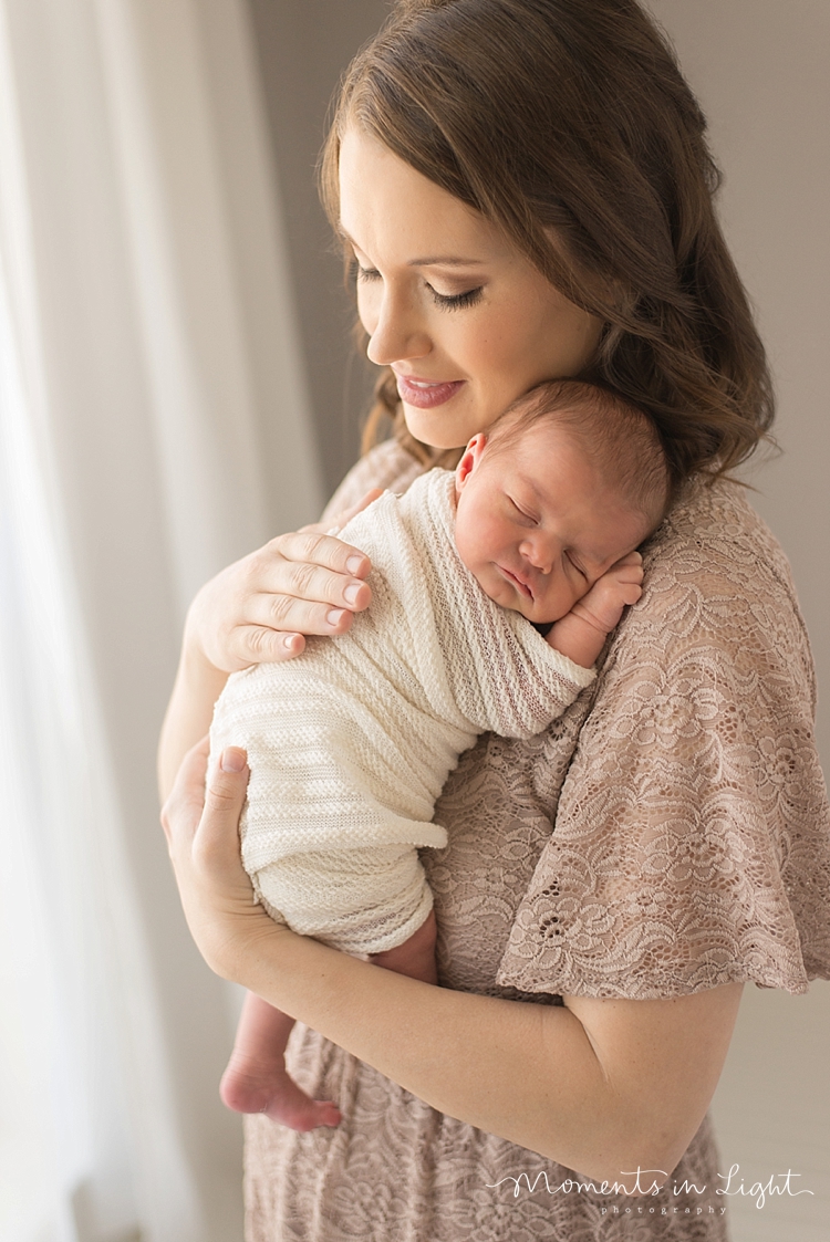 A newborn sleeps on her mom's shoulder during their family with newborn photography session. 