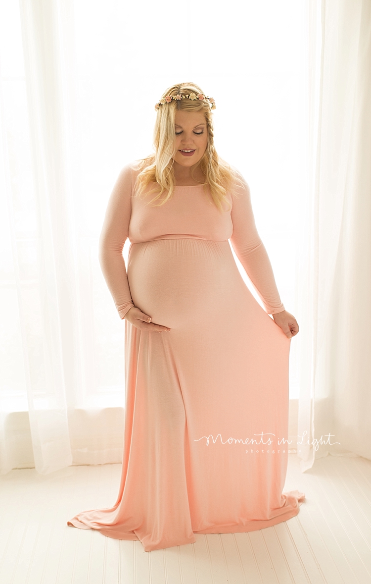 A woman holds her dress out while cradling her tummy for some Maternity Photos In Houston, Texas. 